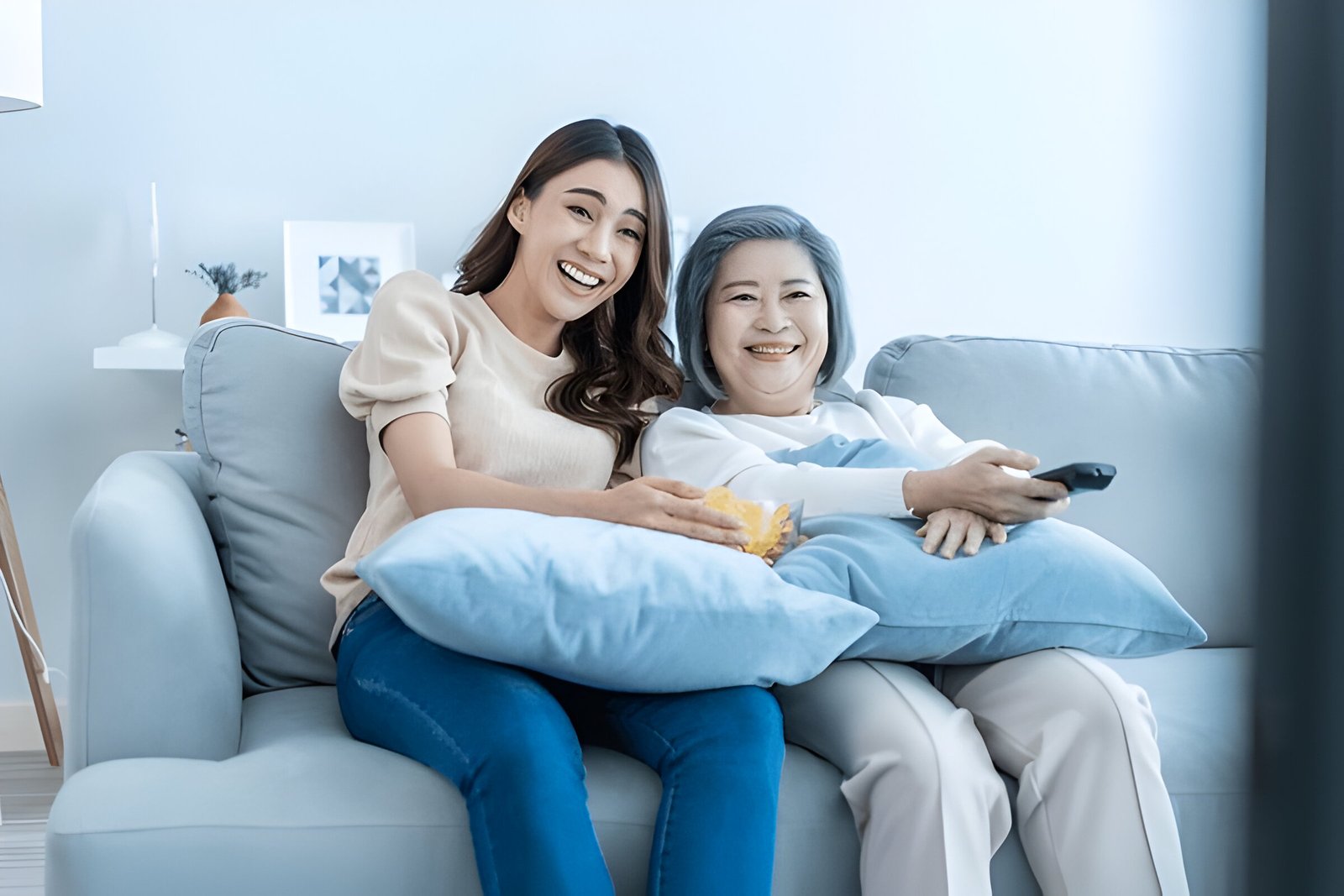Mother and daughter smiling together while relaxing on a sofa at home
